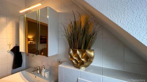 a bathroom with a sink and a vase with a plant at Kungs Ferienwohnung in Cottbus