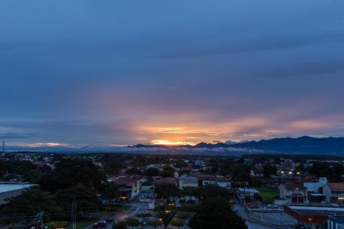 a sunset over a city with mountains in the background at Domum Hotel in Pindamonhangaba