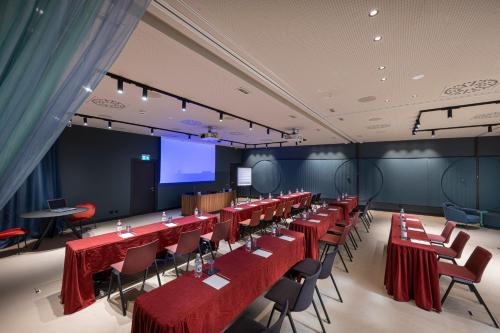 a conference room with red tables and chairs and a screen at LUGANODANTE Boutique & Lifestyle Hotel in Lugano