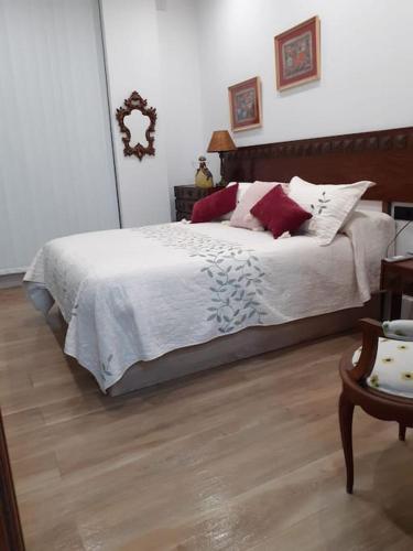 a bedroom with a bed with white sheets and red pillows at Estudio Vandelvira in Baeza