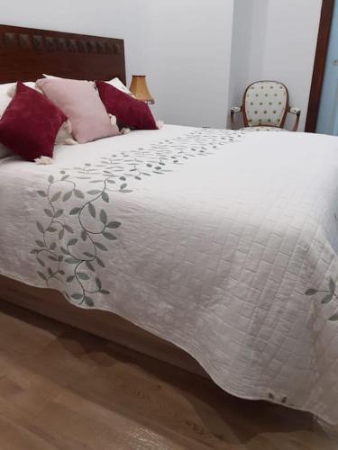 a bed with a white comforter and red pillows at Estudio Vandelvira in Baeza
