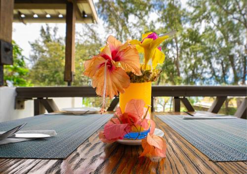 a yellow vase filled with flowers on a table at Le Grand Bleu Hotel in Trou aux Biches