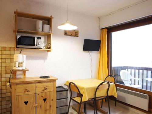une petite cuisine avec une table jaune et une fenêtre dans l'établissement Studio cosy 3 couchages, balcon sud, skis aux pieds, commerces à proximité - Auris en Oisans - FR-1-297-74, à Auris