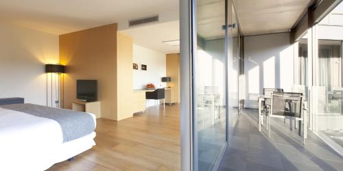 a bedroom with a bed and a kitchen and a living room at Hotel Món Sant Benet in Sant Fruitos de Bages