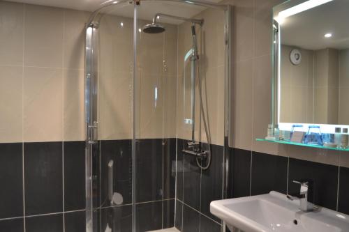 een badkamer met een douche, een wastafel en een spiegel bij The Nags Head in Montgomery