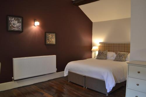 a bedroom with a large white bed and brown walls at The Nags Head in Montgomery