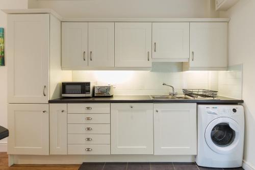 a kitchen with white cabinets and a washing machine at Tegfryn (Sleeps 8), 5*, Sea View, Borth y Gest in Porthmadog