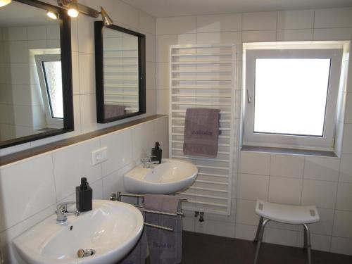 a bathroom with two sinks and a window and a chair at Ferienhaus STICKLIESEL DITZ125 in Ditzum