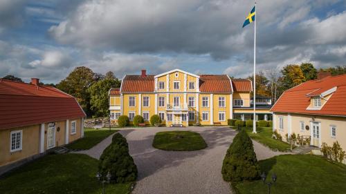un gran edificio amarillo con una bandera delante de él en Ronnums Herrgård, en Vargön