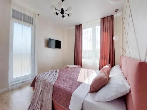 a bedroom with a bed and a tv and windows at VIP Апартаменти Червоної Калини,56а Сихів Новобудова in Lviv