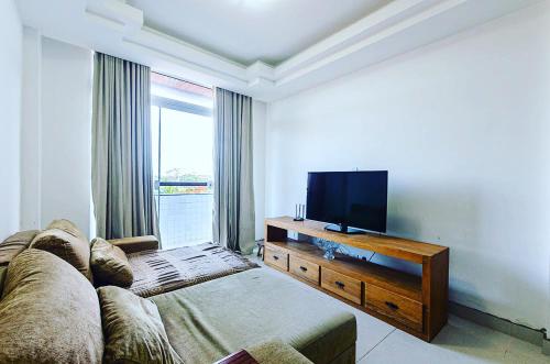 a living room with a couch and a flat screen tv at Excelente apartamento no melhor point de Itaúna a 100 m da praia in Saquarema