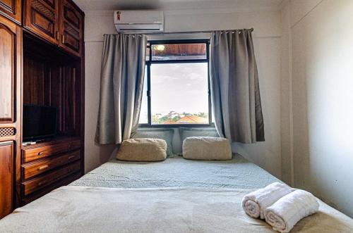 a bedroom with a bed and a window with towels at Excelente apartamento no melhor point de Itaúna a 100 m da praia in Saquarema