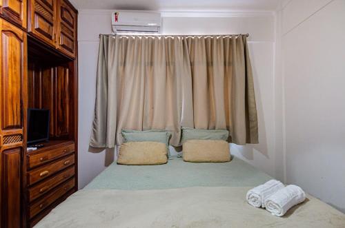 a bedroom with a bed with two pillows and a window at Excelente apartamento no melhor point de Itaúna a 100 m da praia in Saquarema