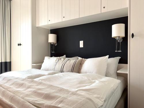 a large white bed in a bedroom with two lamps at NEPTUNE Wenduine met zeezicht - VOSPROPERTIES in Wenduine