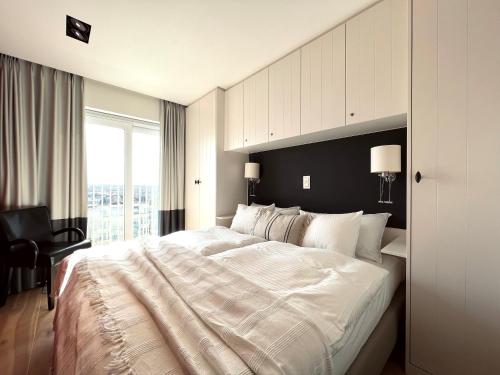 Un dormitorio con una gran cama blanca y una ventana en NEPTUNE Wenduine met zeezicht - VOSPROPERTIES en Wenduine