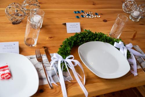a table with white plates and a green wreath at 1852 Landgasthof in Elze