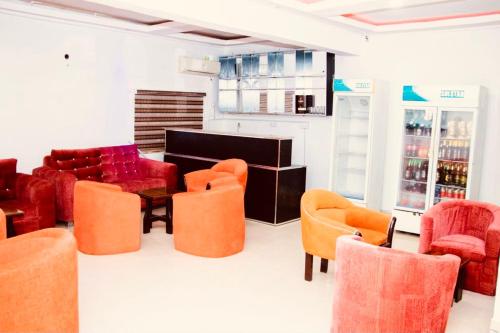 een woonkamer met oranje stoelen en een bank bij E-Gold Luxury Hotel, Maitama in Abuja