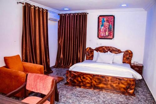 ein Schlafzimmer mit einem Holzbett und einem Stuhl in der Unterkunft E-Gold Luxury Hotel, Maitama in Abuja