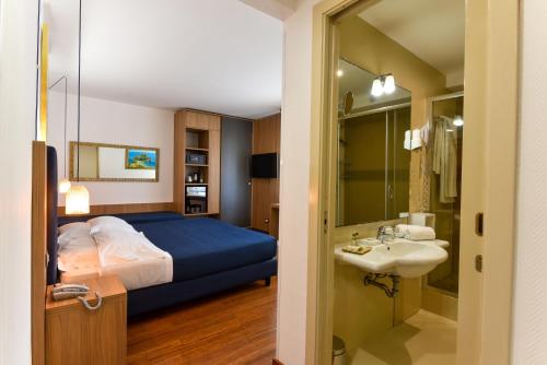 1 dormitorio con cama, lavabo y espejo en Colleverde Park Hotel, en Agrigento