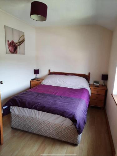 a bedroom with a bed with a purple blanket at SNOWDONIA COTTAGE Glan Gwna Holiday Park in Caernarfon