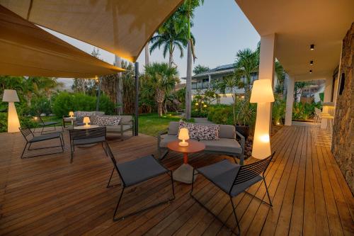 a patio with furniture and tables on a wooden deck at Latitude 21 in Saint-Gilles les Bains