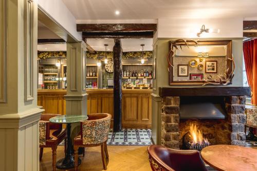 un bar con chimenea, mesa y sillas en The Kings Arms Hotel, en Keswick