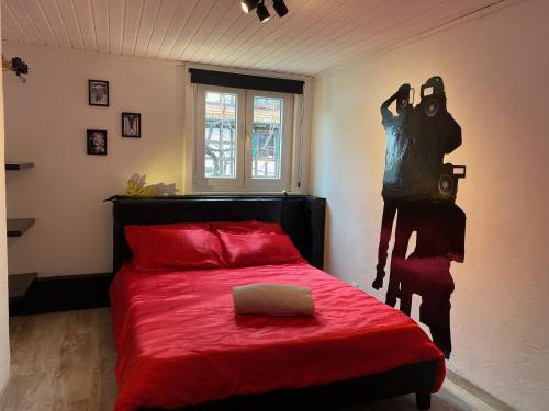 Un dormitorio con una cama roja con una estatua en la pared en Le cinéma, en Soultz-sous-Forêts