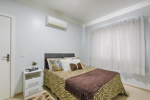 een witte slaapkamer met een bed en een raam bij APT MODERNO À 60 METROS DO TERMAS in Piratuba