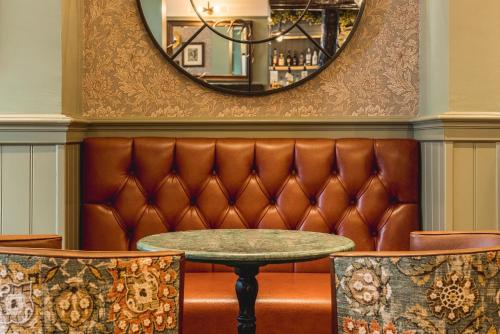 a leather bench with a table and two chairs at The Kings Arms Hotel in Keswick