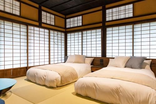 two beds in a room with large windows at Hotel mio in Shimabara