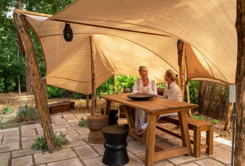 two women sitting at a table in a tent at ZEN-Bungalow NO 4 met sauna en hottub in Rheezerveen