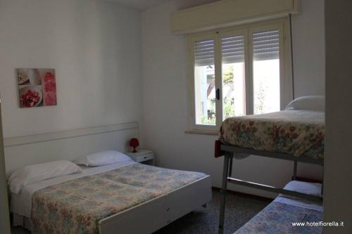 リミニにあるPensione Fiorella Riminiのベッドルーム1室(ベッド2台、窓付)