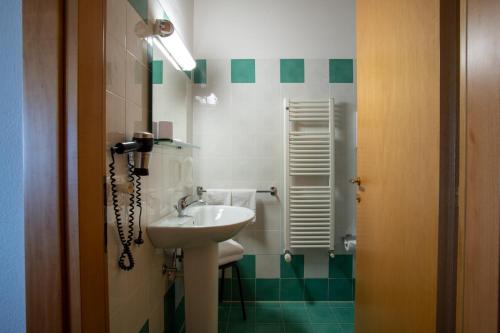 a small bathroom with a sink and a mirror at Hotel Caneo in Fossalòn