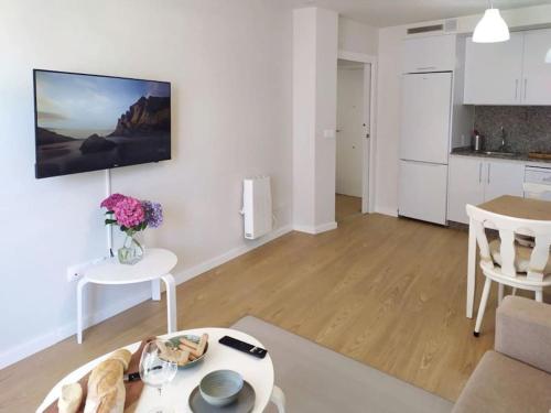 ein Wohnzimmer mit einem Tisch und einer Küche in der Unterkunft 0143 Apartamento nuevo y céntrico in Vigo