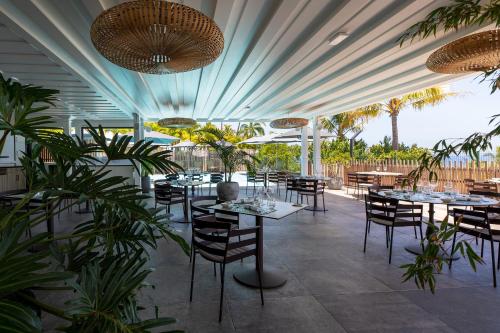 a restaurant with tables and chairs and palm trees at Latitude 21 in Saint-Gilles-les-Bains