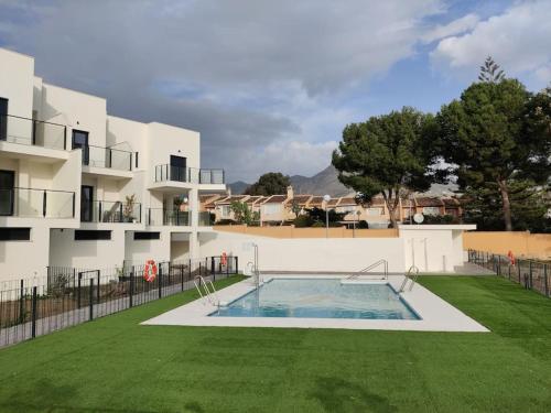 a building with a swimming pool in front of a yard at Benalmadena new terraced house 3 bedroom 2,5 bathroom in Benalmádena