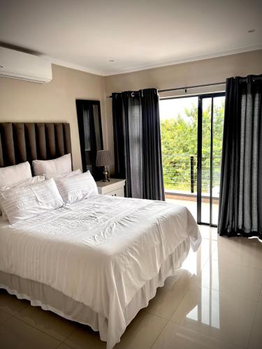 a bedroom with a white bed and a large window at No Load-Shedding Holiday Home in Mataffin