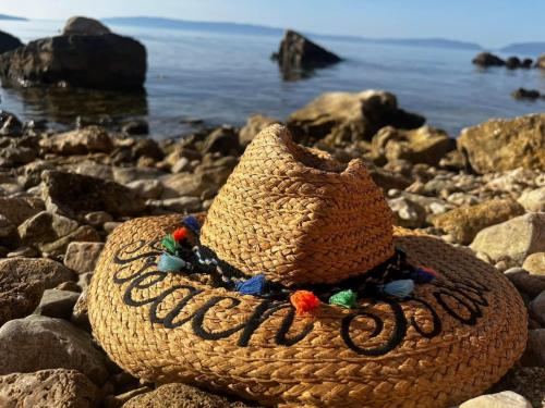 a straw hat sitting on a rocky beach at Cherso Mare in Cres