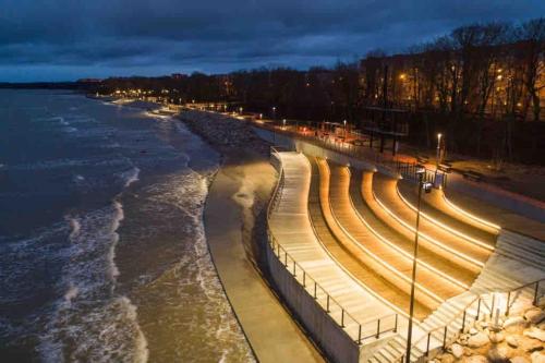 a row of benches next to the water at night at Cozy apartment in a historical town in Sillamäe