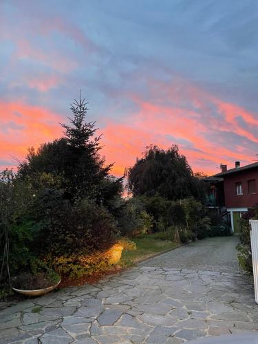 a sunset over a driveway with a tree and a house at B&B Villa Giardini Susanna in Gattico