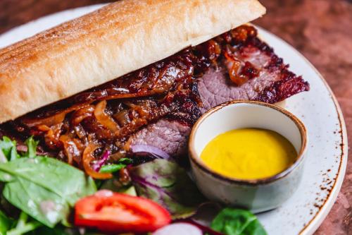 a sandwich on a plate with a salad and sauce at The Kings Arms Hotel in Keswick