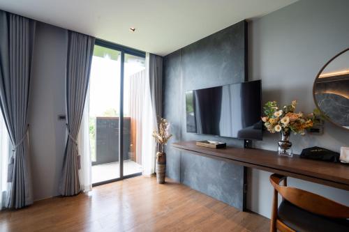 a living room with a television and a desk at Richmann Resort Hotel Hatyai in Hat Yai
