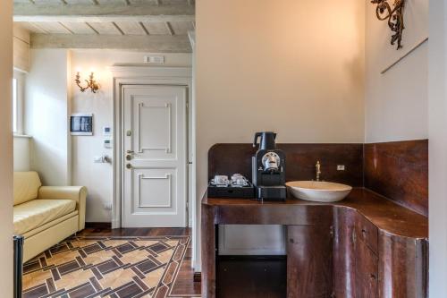 فندق سانتا مارتا سويتس في ميلانو: حمام مع حوض وآلة صنع قهوة على منضدة