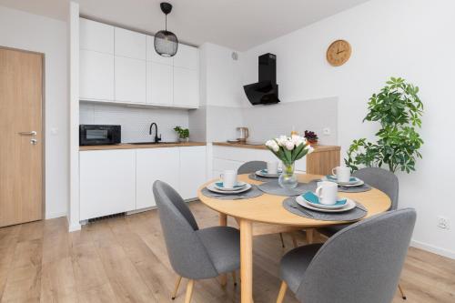 a kitchen and dining room with a wooden table and chairs at Osiedle Latarników Apartment Gdańsk by Renters in Gdańsk