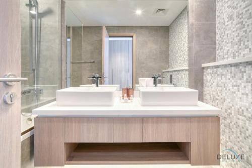 a bathroom with two sinks and a shower at Cosmopolitan 2BR at Stella Maris Dubai Marina by Deluxe Holiday Homes in Dubai