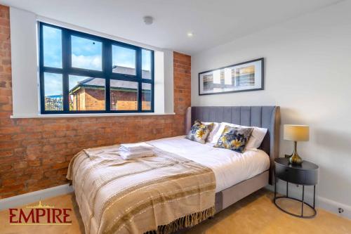 a bedroom with a bed with a brick wall and a window at Brand New 1 Bed Apt Burton On Tr in Burton upon Trent