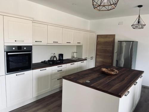 uma cozinha com armários brancos e um balcão de madeira em Apartment Country House Zaton em Tišina