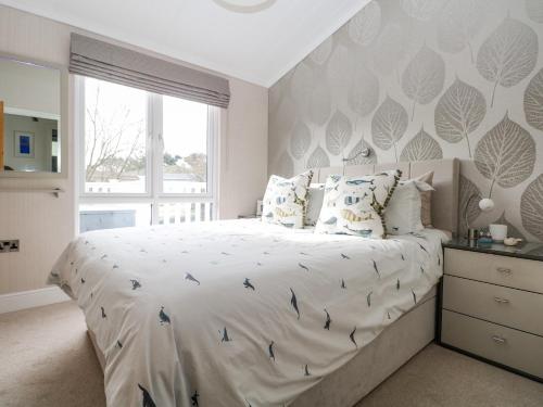 a bedroom with a large bed with a large window at Amberwood 42 in Lymington