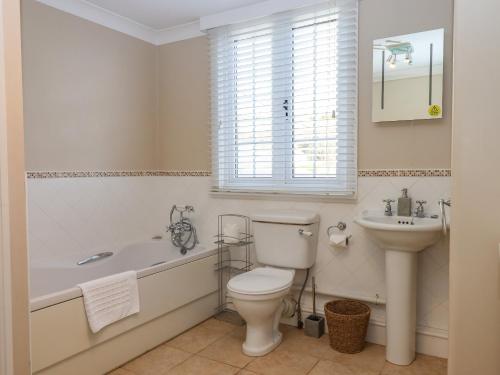 a bathroom with a tub and a toilet and a sink at Early Mist Cottage in Newton Abbot
