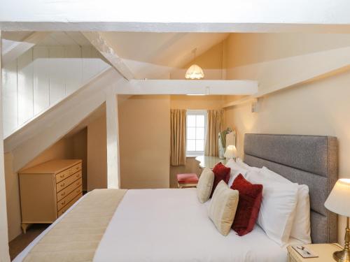 a bedroom with a large white bed with red pillows at Early Mist Cottage in Newton Abbot